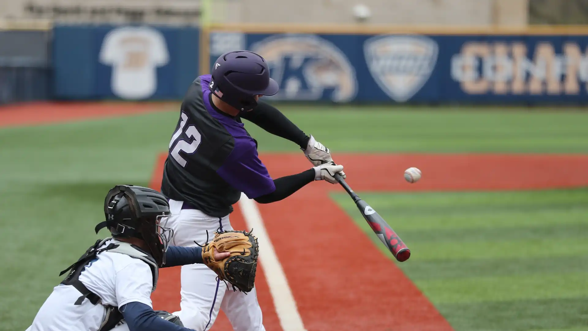 A baseball player is swinging a bat, trying to hit the ball.